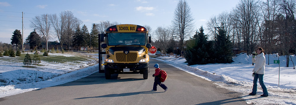 Boy crossing street in front of school bus