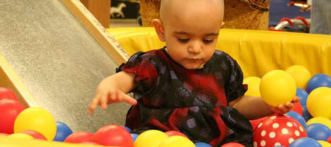 photo of child on slide holding a ball