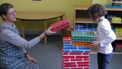 photo of teacher and child building tower of blocks
