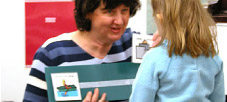 photo of child using a song choice board with teacher